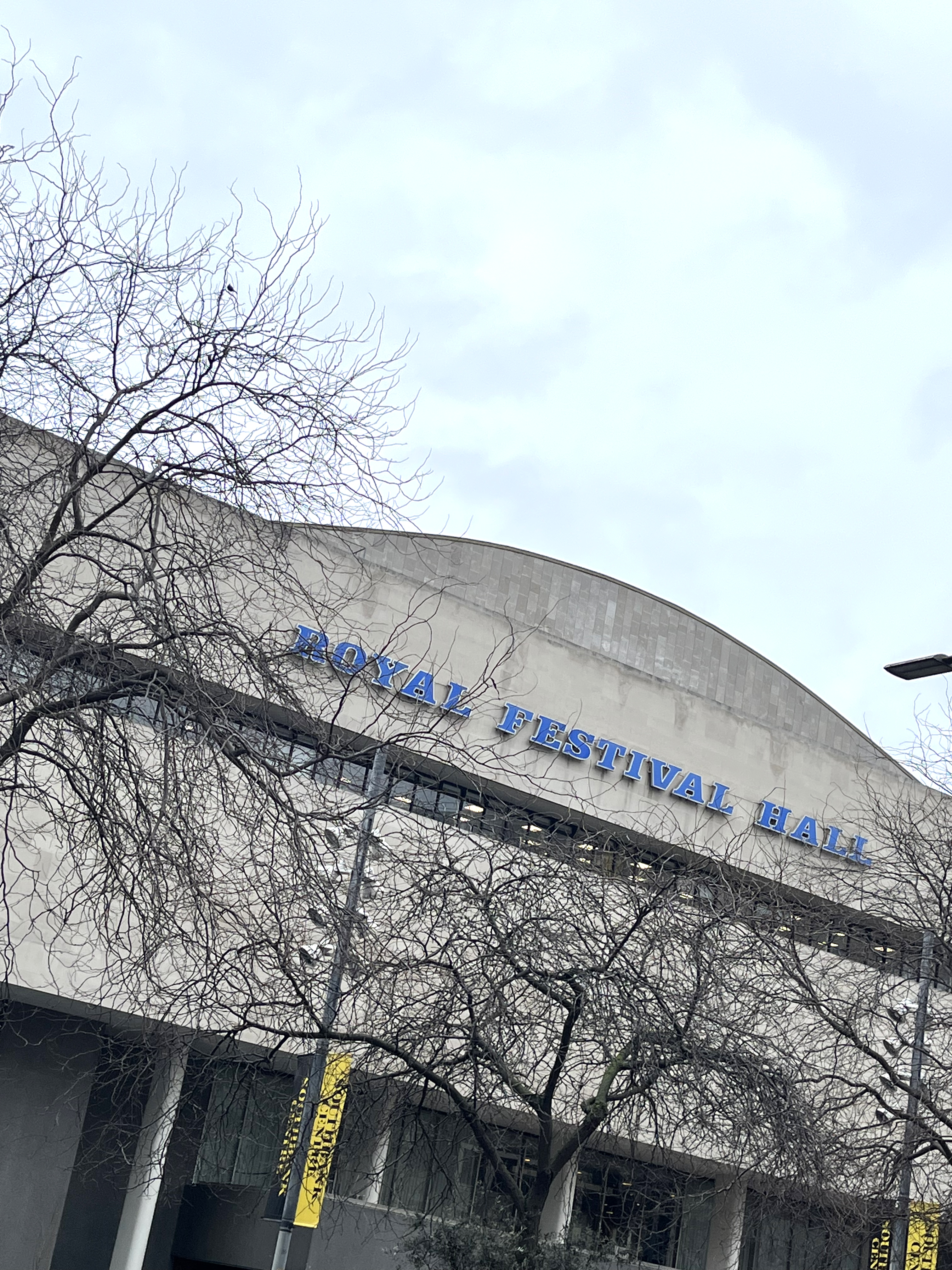 The Royal Festival Hall frontage, showing its blue, italic, slab serif signage reading ROYAL FESTIVAL HALL